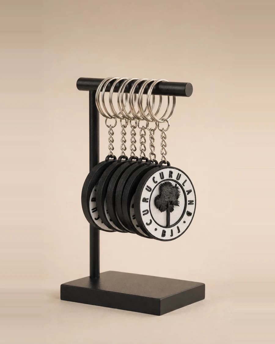 Série de chaveiros personalizados em impressão 3D, pretos e brancos, pendurados em um expositor