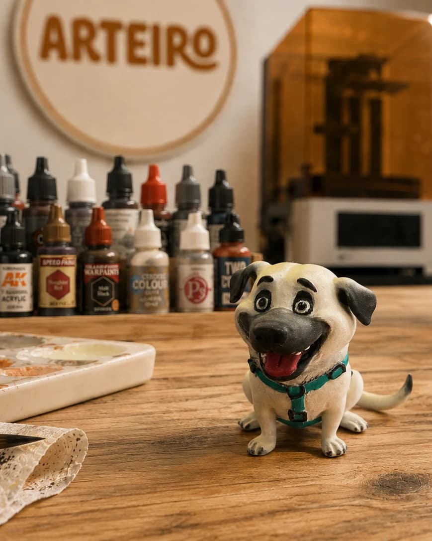 Miniatura personalizada de cachorro bege com peitoral, fotografada na bancada do ateliê