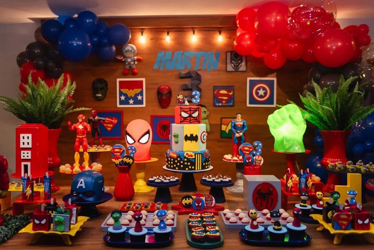Mesa completa da festa de aniversário de super-heróis, com o bolo ao centro e a miniatura personalizada do Martin no topo