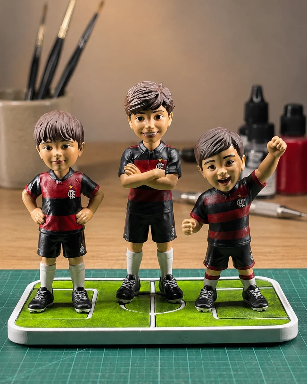 As três miniaturas com o manto rubro-negro vistas de frente sobre a base em forma de campo de futebol