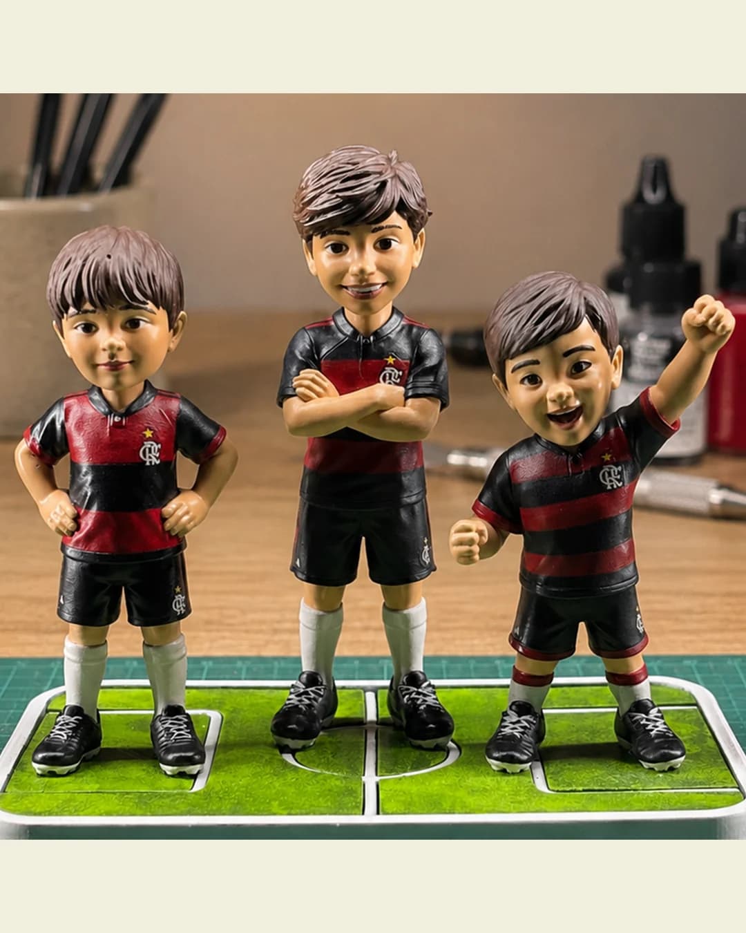 Close das três miniaturas personalizadas de torcedor, mostrando o rosto de cada primo