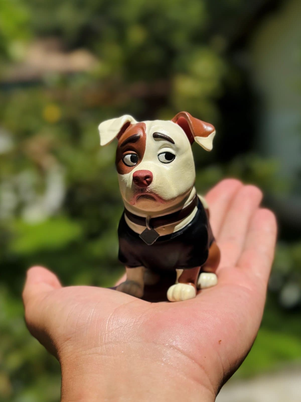 Miniatura do Cleitinho, cachorro do Lucas, segurada na palma da mão ao ar livre